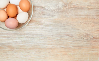 background - a glass bowl with multi-colored eggs stands on a wooden surface