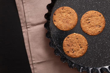 Oatmeal cookies and chocolate chips on black background