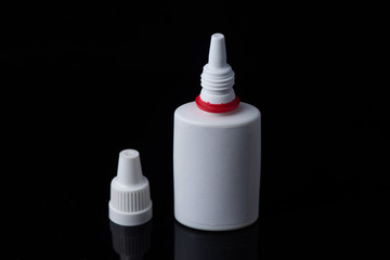 White plastic medical container on white, black background..nasal spray