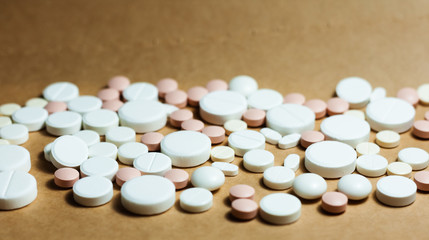 Heap of white pills, tablets, capsules on yellow orange background. Drug prescription for treatment medication health care concept wth copy space.