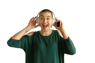 Listening to music. Portrait of young caucasian woman with freaky appearance on white background. Unusual look with tattoos and bald. Human emotions, facial expression,sales, ad concept. Youth culture