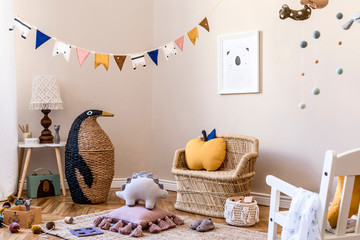 Stylish scandinavian interior of child room with natural toys, hanging decoration, design furniture, plush animals, teddy bears, mock up poster and accessories at modern home decor.