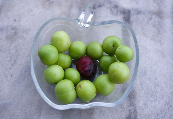 Heap of green sourish plums in glass bowl pot on white background. Fresh, organic and clean eating, healthy lifestyle conceptual photo. Agricultural background concept. To be different from others.	
