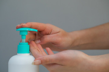 Woman Hands using wash hand sanitizer gel pump dispenser. Clear sanitizer in pump bottle, for killing germs, bacteria and virus
