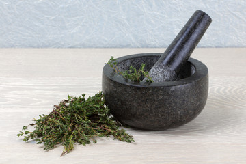 thyme on wooden kitchen surface and mortar and pestle