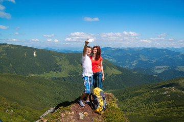 Happy couple hugging in the top of mountain and do selfie photo.