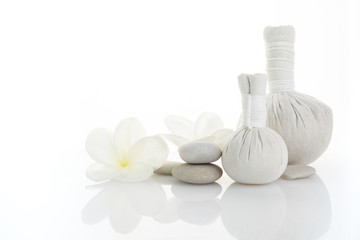 Fototapeta na wymiar Spa white background plumeria and herbal compress balls. Spa massage. Zen stones balance.