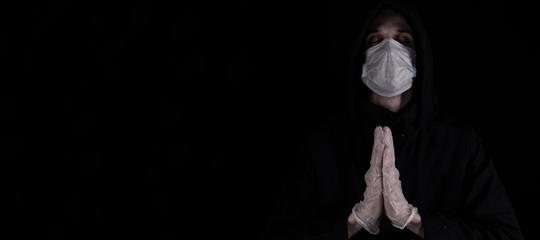 Close up profile portrait of man in the hood wearing medical mask and gloves. Dark background....