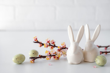 Easter spring decorative composition  with white easter ceramic bunny,  pink cherry branch. On a white background with place for text.