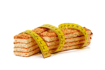 two pieces of layered honey cake isolated wrapped by meter tape on white background