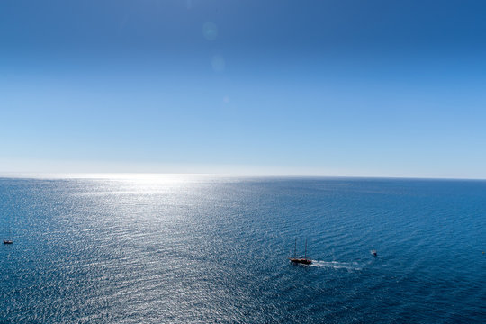 Several food processing boats moored in the distance at sea during the night illuminated by the lights glowing on the horizon during high tid
