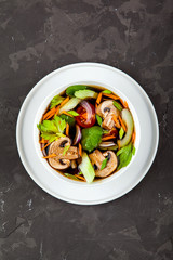 Traditional asian noodle soup pho in bowl, vegetables, mushrooms on concrete background. Asian food concept.