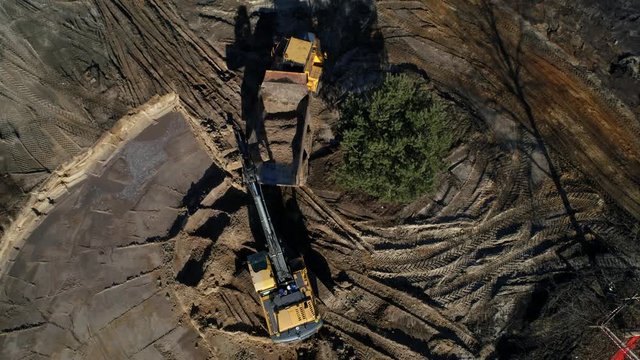 Aerial top down shot of a excavator loading dirt on a big truck