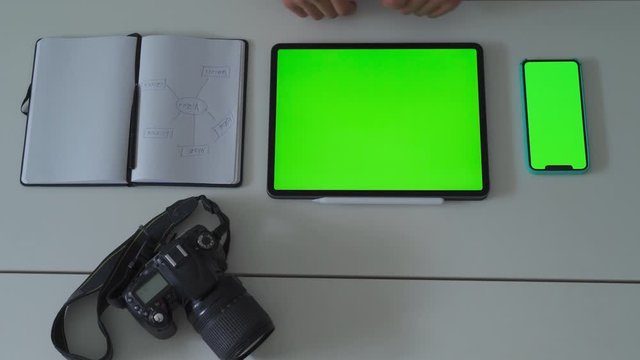 Photographer working with his mobile devices and his camera. Green screen