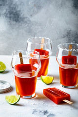 Latin american beer drink Michelada with salt rim and spicy tomato juice popsicles. Summer alcohol cocktail michelada or Mexican bloody beer.