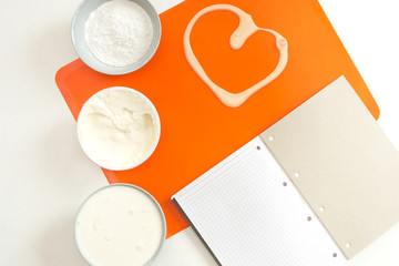 recipe step by step layout of products for cream on a silicone orange mat mascarpone cream for baking powdered sugar top view
