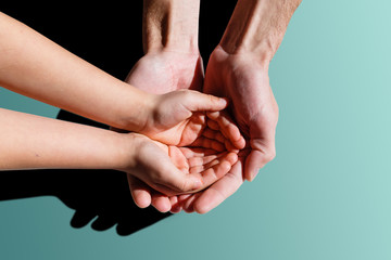 A closeup family photograph of a dad or father holding his infant boy or son's tiny open baby hand and fingers in his palm.