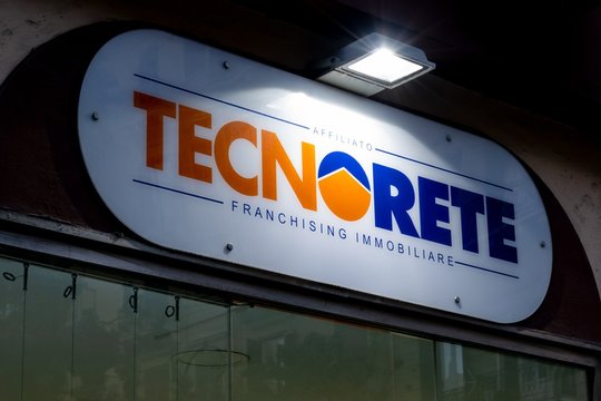 The logo of Italian Tecnorete real estate company store (Franchising Immobiliare) which sells houses at night with a light above