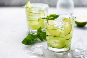 Summer homemade lemonade made from lime, lemon, cucumber and basil with ice in glass on an old...