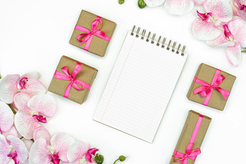 Fototapeta na wymiar flat lay of Gift present boxes with pink ribbon and orchid flowers. Note book or diary writing. spring concept