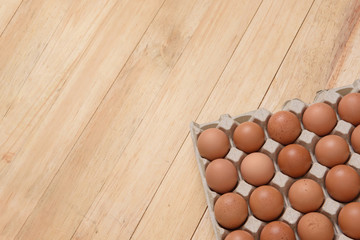 Chicken eggs in carton on wooden background, top view, copy space for text
