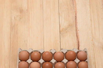 Chicken eggs in carton on wooden background, top view and copy space for text