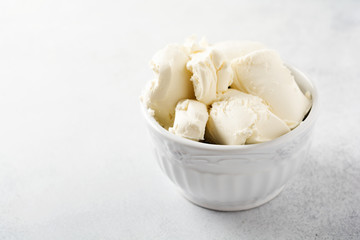 Fresh mascarpone cheese in a white bowl for making Italian tiramisu dessert on light background. Selective focus.
