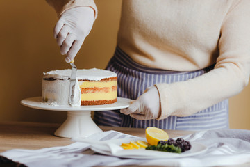 Woman housewife spreading the icing to cover the top of the cake. Housewife smoothing surface using spatula, close up cropped photo. Free time on quarantine. Recipe of home cooking cake.