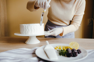 Housewife is cooking homemade lemon cake. Above view of human hands busy with pastry cooking using knife. Recipe of organic cake.