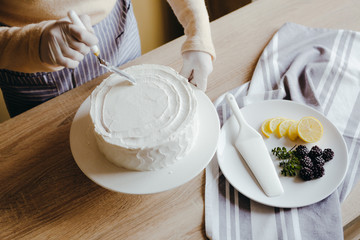 Housewife is cooking homemade lemon cake. Above view of human hands busy with pastry cooking using knife. Recipe of organic cake.