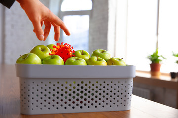 Coronavirus hiding in usual things - check cleanse and freshness of your fruits and food. Human hand's going to take apple, orange or lemon from the table. Pandemic, epidemic concept, disinfecting.