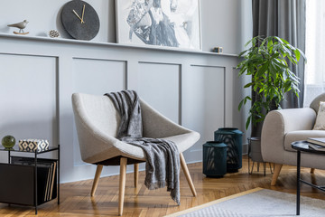 Stylish scandinavian home interior of living room with design gray sofa, armchair, marble stool, black coffee table, modern paintings, decoration, plant and elegant personal accessories in home decor.