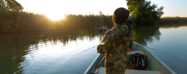 Anglers fishing from the boat on the calm river in Astrakhan Region in Russia. Astrakhan is a...