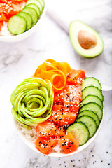 Salmon poke with avocado, cucumber, and rice on marble background , top view. Asian trendy food