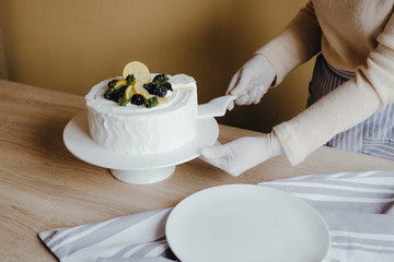 Housewife taking slice of fresh delicious birthday homemade lemon cake at table, top view. Concept of home cooking on qurantine. Recipe of lemon organic cake.