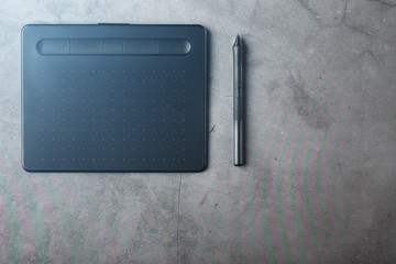 Graphic tablet with a stylus on a dark textural background, top view. Gadget for working as a designer, artist and photographer