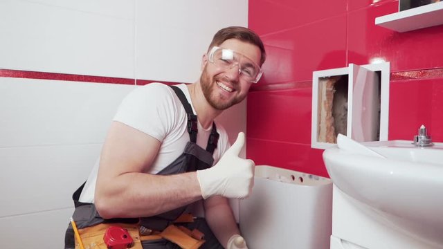 A professional plumber in the toilet shows his thumb up