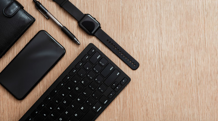 Flat lay composition with black pen, computer keyboard, smart watch, smartphone and leather wallet on a wooden surface. Business concept. Business people items. Free space for text. 