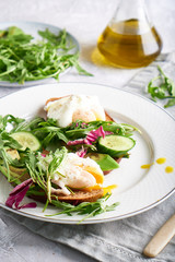 Poached eggs with herbs, avocado and cucumber served on a plate on a light background Copy space