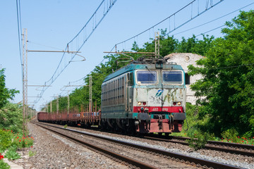 Un treno merci con carico di barre di acciaio in transito nei pressi di Latina, Italia