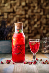 Side view on fresh cool orange berry lemonade with mint on the wooden table, vertical