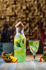 Side view on fresh cool kiwi lemonade with mint on the wooden table, vertical
