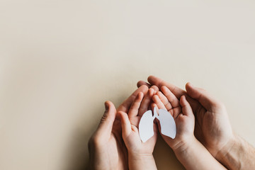 small white lungs of paper lie on the hands of people on a light background top view