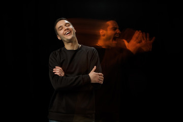 Laughting outside, screaming inside. The versatility of man - opened emotions and hidden feelings. Caucasian man on black background with different faces of condition. Double exposure. Mental health.