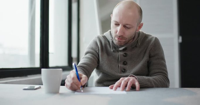 A man sits at a table, thinks and writes, enjoys ideas that come to mind. The screenwriter creates the script.