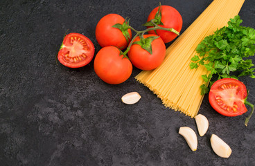 
Spaghetti. Ingredients for pasta on a black background. (tomatoes, herbs, spices, garlic). Copy space.