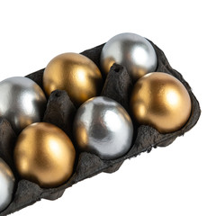 Easter gold eggs in a black carton container on white background.