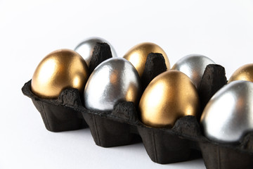 Easter gold eggs in a black carton container on white background.