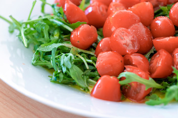 Cherry tomato and arugula salad on a white plate close-up