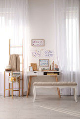 Stylish room interior with creative workplace near white wall